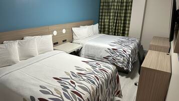 A hotel room with two beds, a small table, a wooden cabinet, and a television.