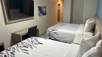 Habitación de hotel con dos camas, un televisor, un escritorio y un espejo.