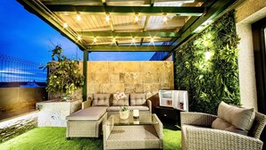 An outdoor patio with wicker furniture, a glass-top coffee table, and a refrigerator. - Lucus Skyline by Lugo Collection (Lugo)