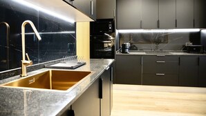 A modern kitchen with a gold sink, black cabinets, and a built-in oven. - Lucus Skyline by Lugo Collection (Lugo)