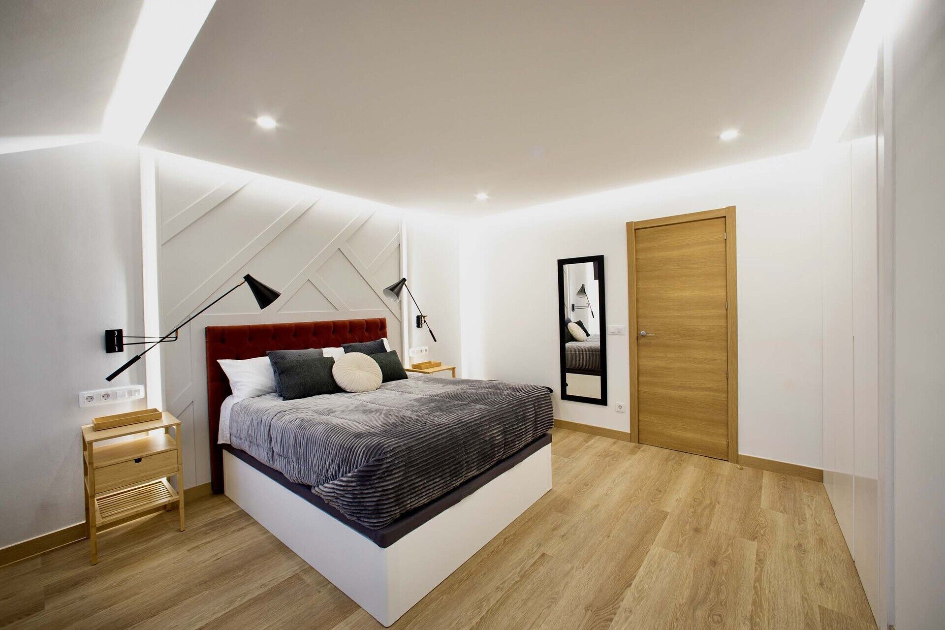 Camera da letto moderna con un letto grande, comodini, un'armadio in legno e un lampadario.