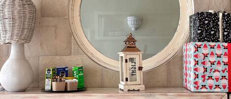 A room with a large mirror, a bookshelf filled with books, a decorative lamp, and a small lantern on the shelf.