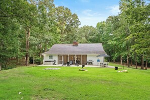Ein eingeschossiges Haus mit überdachter Veranda, Grill und Terrassenbereich.