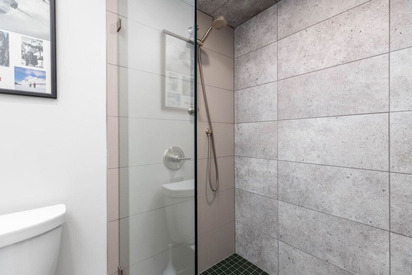 A shower area with a glass door, tiled walls, and a visible toilet.