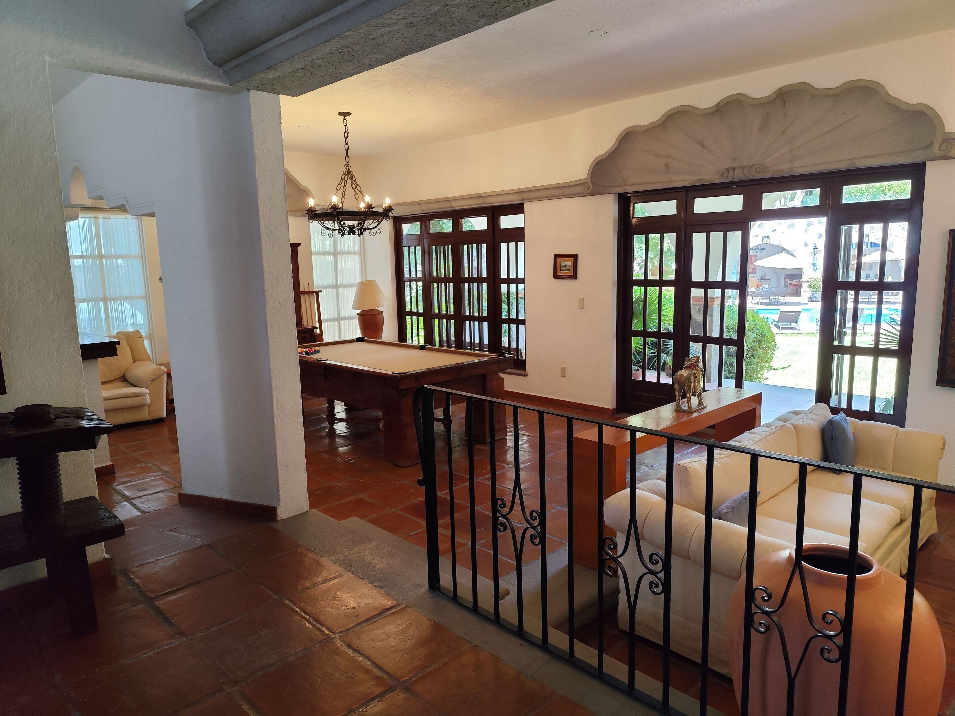 A spacious living area with a pool table, a sofa, and a dining table.