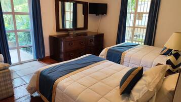 A hotel room with two beds, a dresser, a television, and a view of the outdoors.