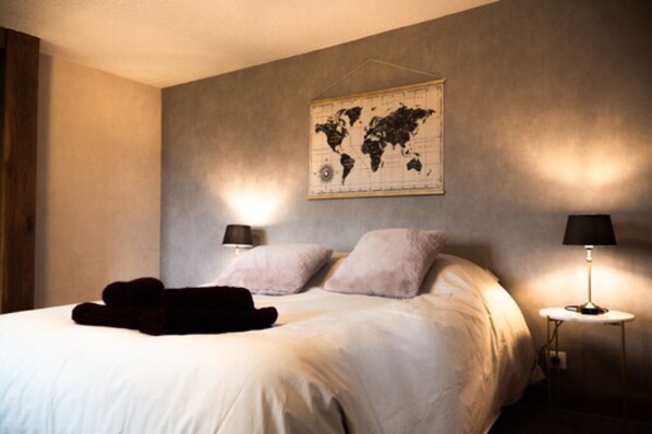 A bedroom with a large bed, two bedside lamps, a world map on the wall, and a dark throw blanket on the bed. - House 5 minutes from Lac du Der! (Voillecomte)