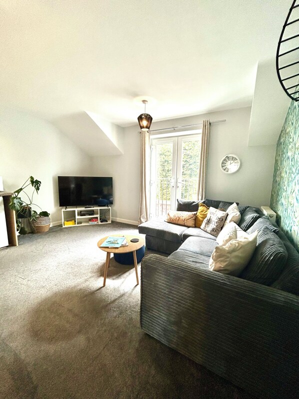 A living room with a sofa, a television, a small table, and a plant.