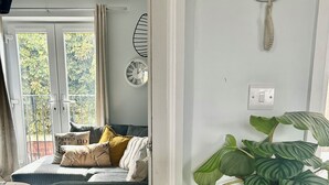 Una habitación con cama, una mesa redonda, una planta en maceta, un reloj de pared y un teléfono.