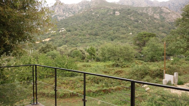 A wooden deck with a metal railing overlooking a mountainous landscape. - Recent 90 m2 house in a tourist village 20 minutes from the beach (Feliceto)