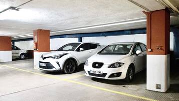 Un parking avec deux voitures blanches garées sous des piliers.