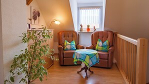 Una habitación acogedora con dos sillones de cuero, una mesita, una planta en maceta y una ventana con cortinas.