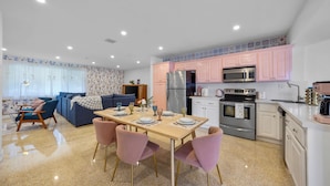 A modern kitchen with pink cabinets, a stainless steel refrigerator, and a microwave.