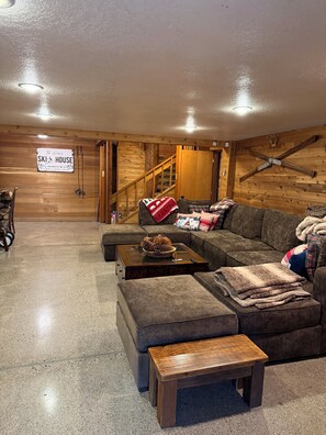 Una sala de estar acogedora con una escalera de madera, un letrero que dice 'The Poo's Ski House' y decoración temática de esquí.