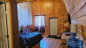 A cozy room with a bed, a desk, and a water dispenser.