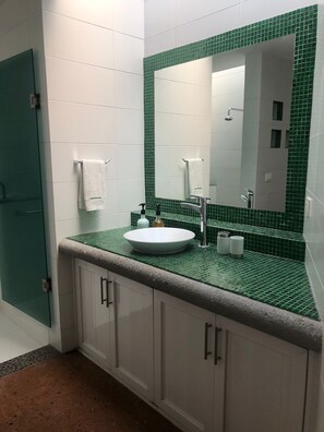 Bathroom features a large mirror, white sink, and green-tiled backsplash.