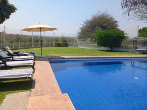 Relax by the clear pool surrounded by lush greenery and comfortable sun loungers.
