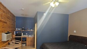 A compact room with a bed, a kitchenette, a small table, and chairs. - Barn In The Bush- Room 2 Lower level 2 queen beds (Russell)