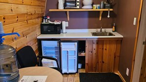A compact kitchen with wooden walls, a microwave, a toaster, and a sink. - Barn In The Bush - Room 4, King, queen & futon (Russell)