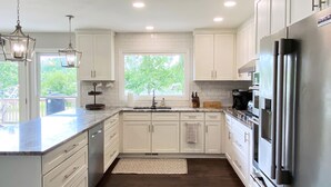 Una cocina moderna con armarios blancos, electrodomésticos de acero inoxidable y un ventanal que proporciona luz natural.