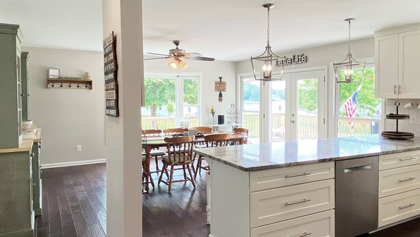 Una cocina amplia con una isla grande, armarios blancos y una zona de comedor con sillas de madera.