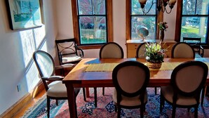 A dining room with a wooden table, six chairs, a globe, and a vase with flowers.