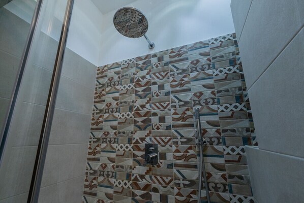 Ducha con pared de azulejos estampados y cabezal de ducha manual.