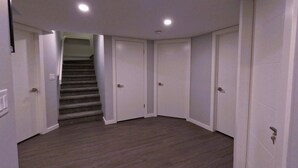 Un couloir doté d’un sol recouvert de moquette, de portes blanches et d’un escalier menant à un autre niveau.