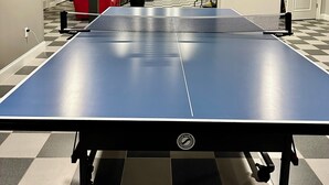A ping pong table in a room with a checkered floor, a fireplace, and red chairs. - Waterfront, private, 2 bedroom apartment - SUMMER DATES AVAILABLE! (Wareham)