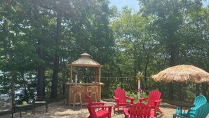 An outdoor seating area with Adirondack chairs, a wooden gazebo, and a thatched umbrella. - Waterfront, private, 2 bedroom apartment - SUMMER DATES AVAILABLE! (Wareham)