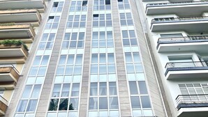 A multi-story building with a modern architectural design, featuring a grid of windows and balconies on each floor. - Rosalia Park by Lugo Collection (Unknown)