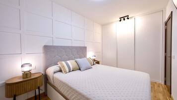 Un dormitorio con una cama grande, una mesita de noche con lámpara, un armario y una lámpara en el techo.