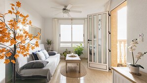 A bright living room with a sofa, a coffee table, a ceiling fan, and a large window. - The Charm of Val-calm and sea views in Bolnuevo (Bolnuevo)