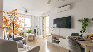 A modern living room with a sofa, a dining table, and a TV mounted on the wall. - The Charm of Val-calm and sea views in Bolnuevo (Bolnuevo)
