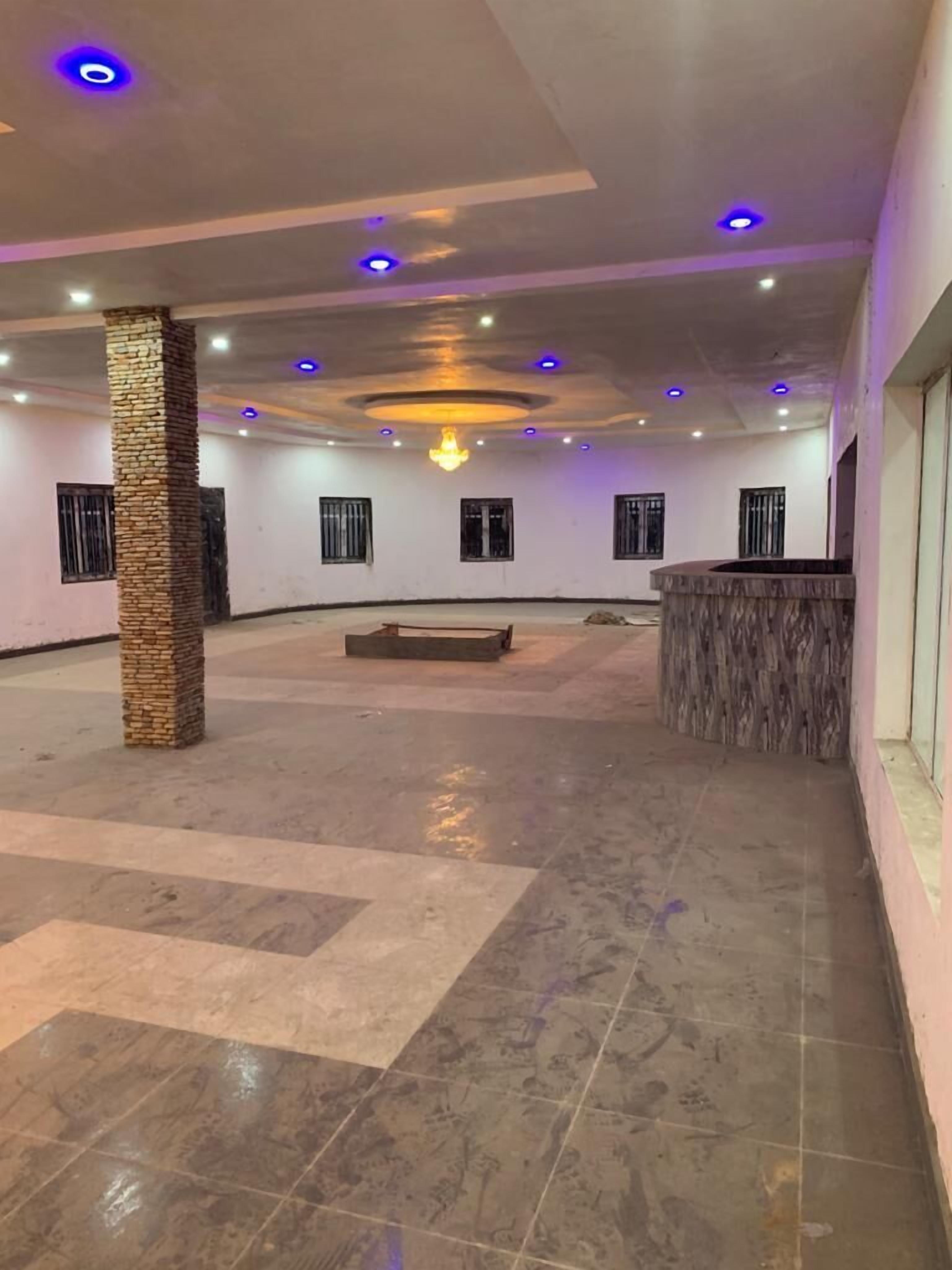 Un amplio salón con techo alto, iluminación empotrada y un candelabro central.