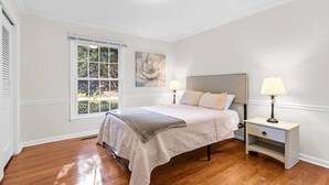 Una camera da letto con un letto, due lampade da comodino, una finestra e una luce a soffitto.