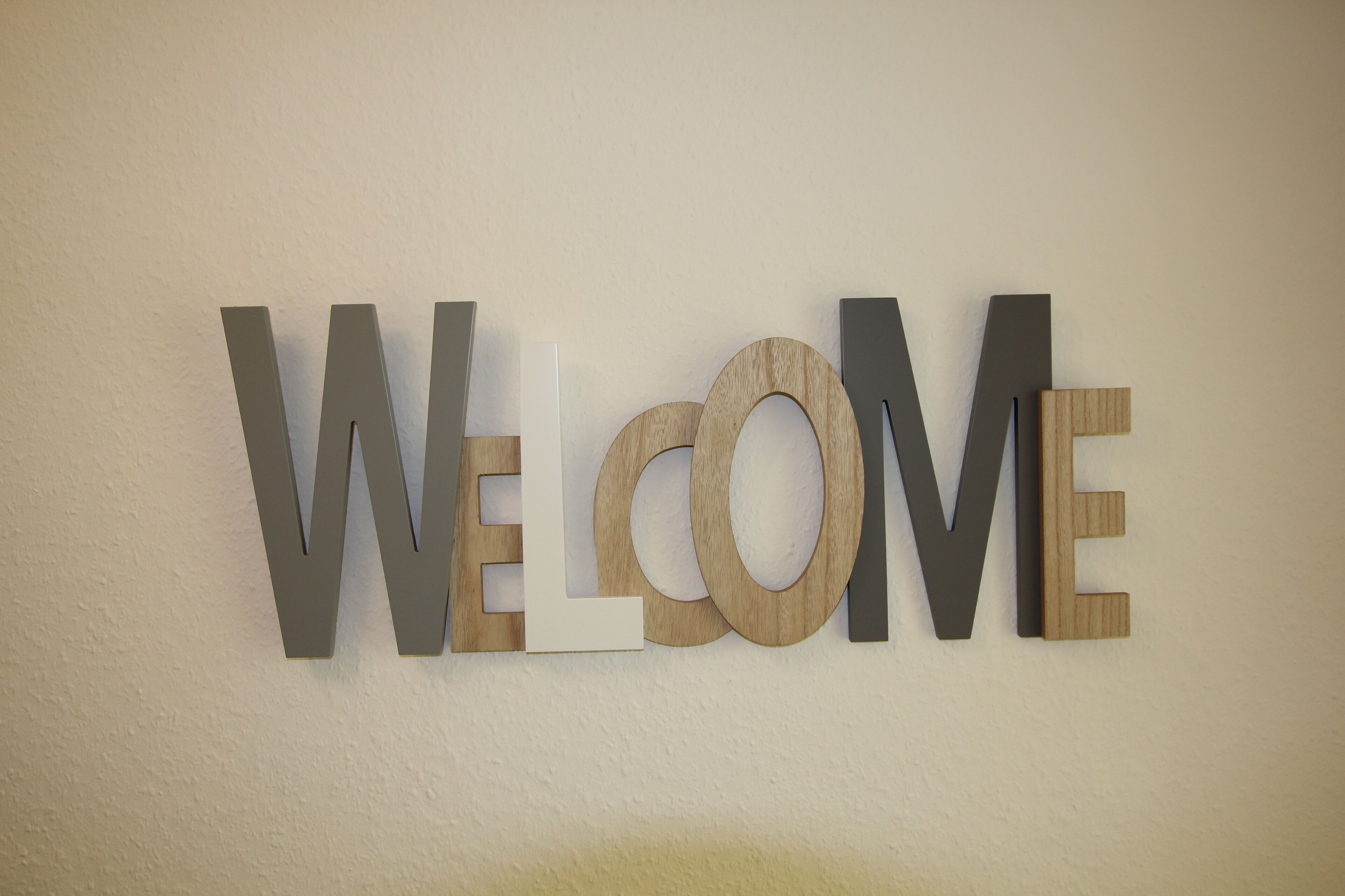 A wall-mounted sign with the word "WELCOME" in large, mixed-material letters.
