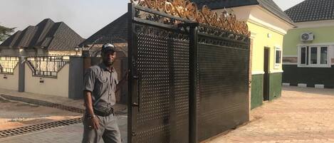 A security guard standing in front of a gated entrance with decorative metalwork.