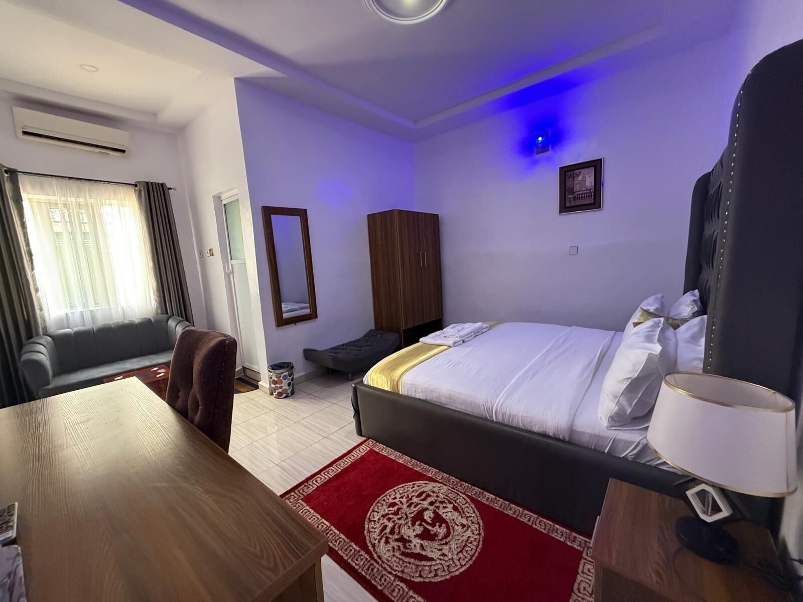 Une chambre d’hôtel équipée d’un lit, d’un bureau, d’une chaise, d’un canapé, d’une armoire et d’un miroir.