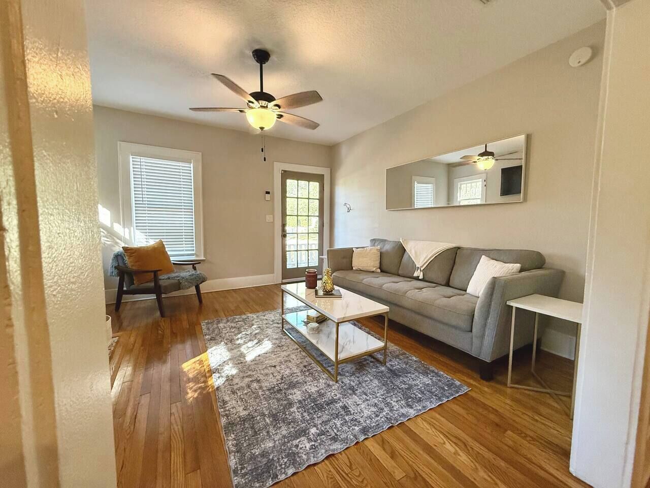 A living room with a sofa, coffee table, and a ceiling fan.