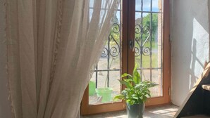 A room with a window, a curtain, a potted plant, and a staircase.
