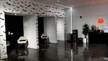 A modern interior with a polished marble floor, a reception area with a neon sign, and a wall decorated with bat silhouettes.