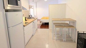 A compact kitchen with a microwave, sink, and a small dining area with a table and benches. - Casa Fita Santillana del Mar  (Santillana del Mar)