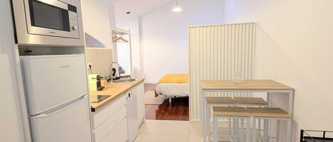 A compact kitchen with a microwave, sink, and a small dining area with a table and benches.