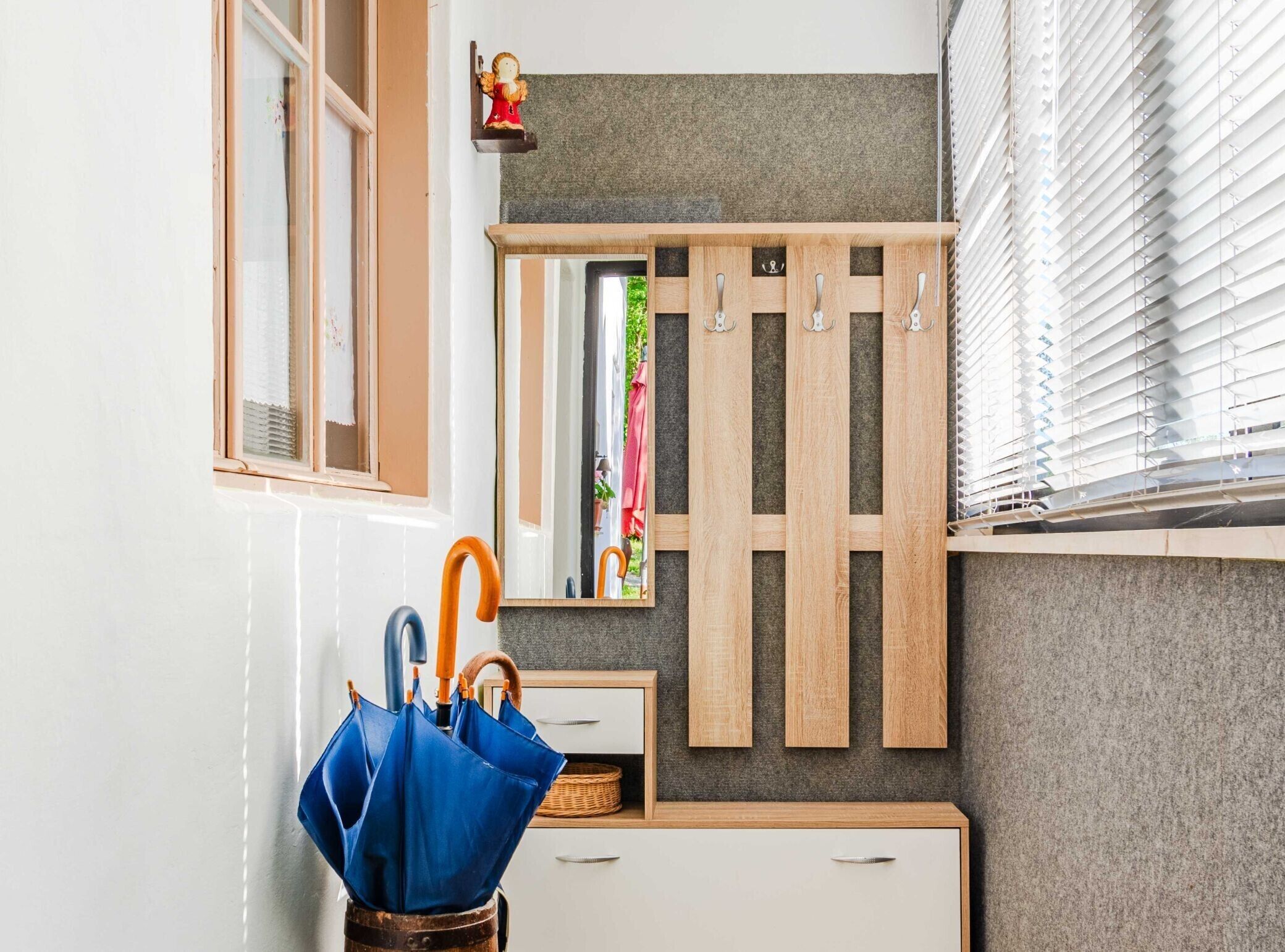 A bathroom with a wooden cabinet, a mirror, and a blue umbrella.