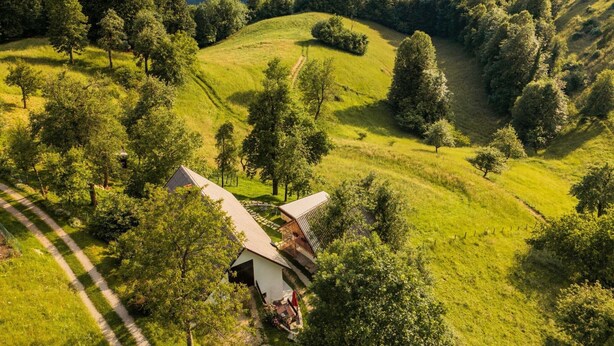 Une maison isolée, entourée de collines verdoyantes et d’arbres luxuriants.