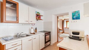 Une cuisine compacte avec des meubles blancs, un four encastré, un four à micro-ondes et un petit plan de travail.