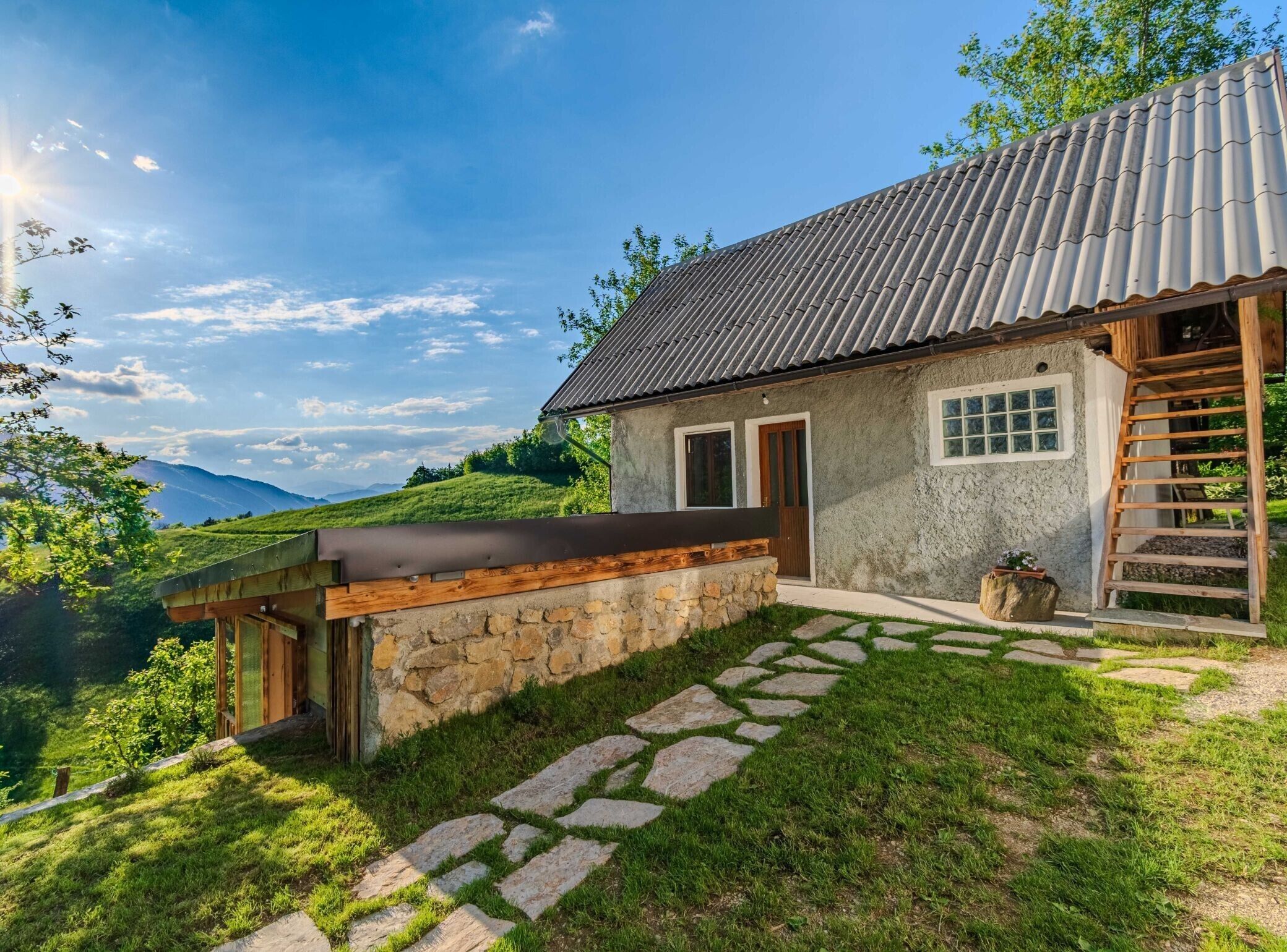 A rustic house with a stone facade, a metal roof, and a wooden deck.