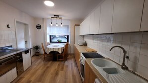 A compact kitchen with a dining table, wooden cabinets, a sink, and a stove.