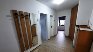 A hallway with wooden flooring, white walls, and a wooden cabinet with a small statue on top.